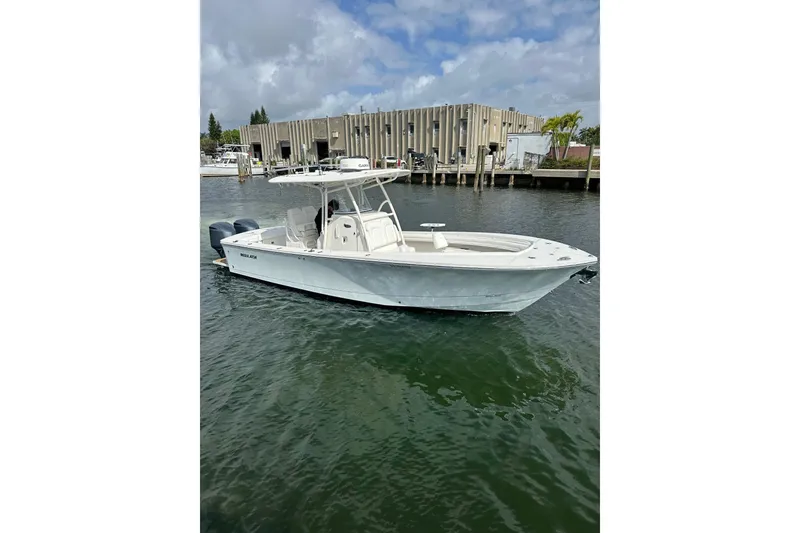 The Image of 2017 Regulator 28 boat on water near a dock, under cloudy skies. - 0