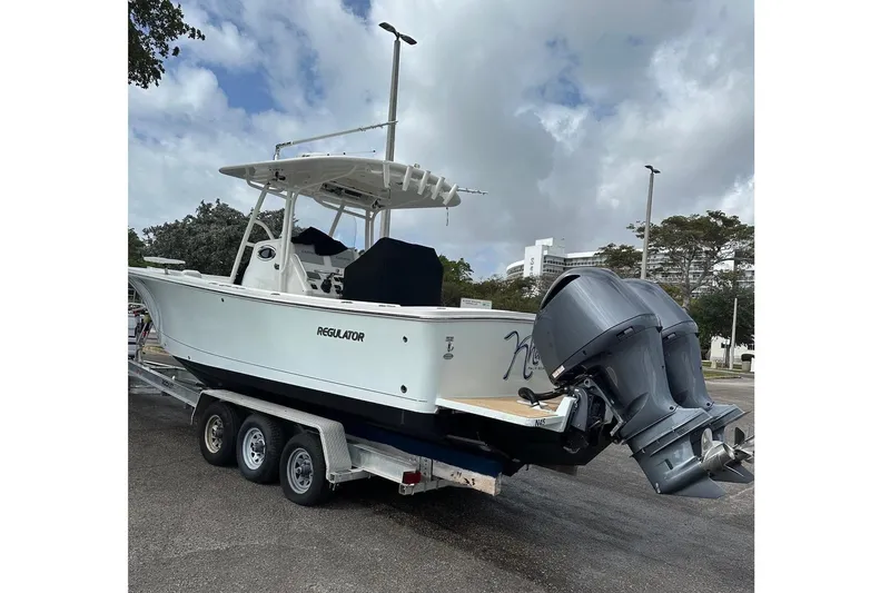 Slide: The Image of 2017 Regulator 28 boat on trailer with dual outboard motors, parked outdoors. - 9