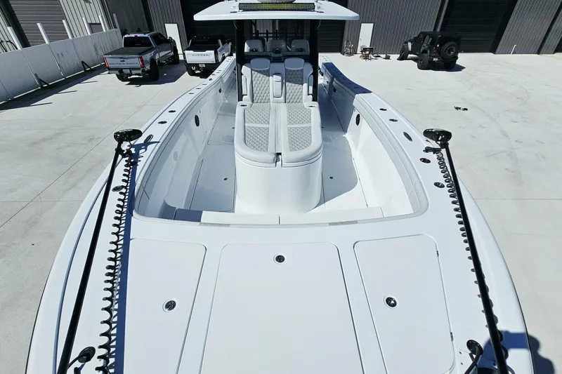 Slide: The Image of 2025 Costa Custom Boats 34ST, sleek white design, docked with vehicles in the background. - 10