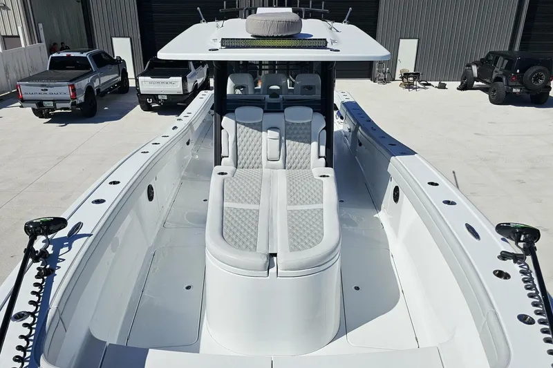 Slide: The Image of 2025 Costa Custom Boats 34ST, sleek white design, spacious deck, parked near trucks. - 11