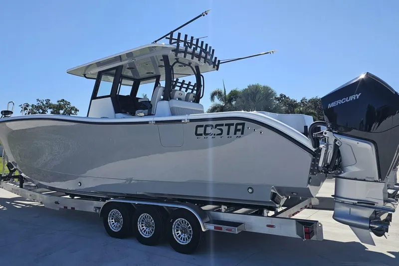 Slide: The Image of 2025 Costa Custom Boats 34ST on trailer, featuring Mercury outboard engine. - 2