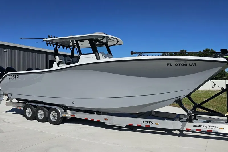 Slide: The Image of 2025 Costa Custom Boats 34ST on trailer, sleek design, parked outdoors under clear blue sky. - 5