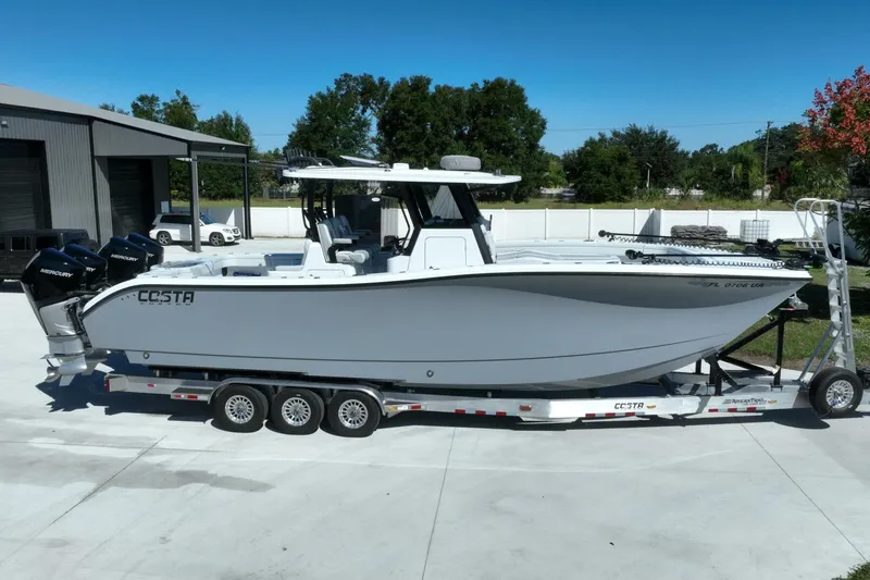 Slide: The Image of 2025 Costa Custom Boats 34ST on trailer, parked outdoors under clear blue sky. - 56