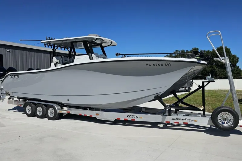 Slide: The Image of 2025 Costa Custom Boats 34ST on trailer, sleek design, parked outdoors under clear blue sky. - 6