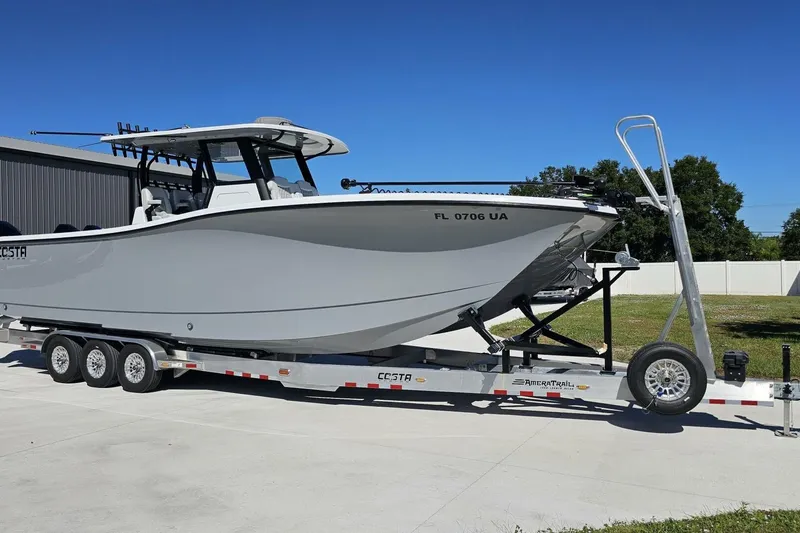 Slide: The Image of 2025 Costa Custom Boats 34ST on trailer, parked outdoors under clear blue sky. - 7