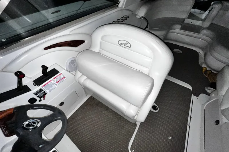 Slide: The Image of 2004 Sea Ray 290 Bowrider interior with white seating and steering wheel. - 23