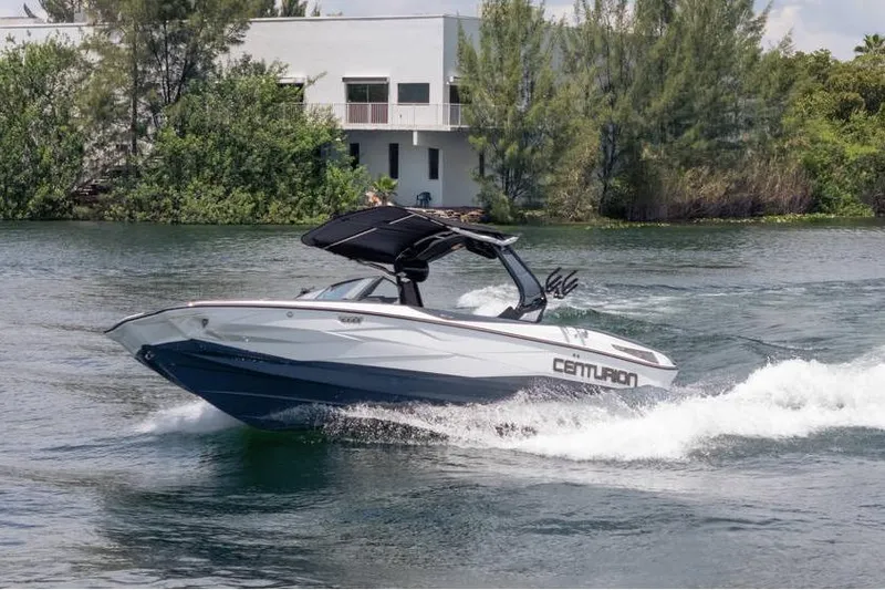 Slide: The Image of 2025 Centurion Nv233 boat cruising on a scenic waterway near lush greenery. - 10