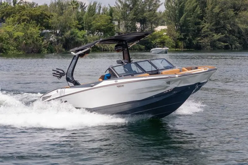 Slide: The Image of 2025 Centurion Nv233 boat cruising on a scenic lake with lush greenery. - 12