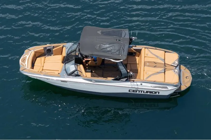 Slide: The Image of 2025 Centurion Nv233 boat on water, featuring tan seating and black canopy. - 18