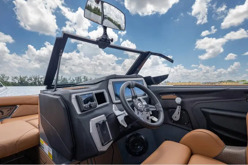 Slide: The Image of 2025 Centurion Nv233 boat interior with modern dashboard and steering, under a bright blue sky. - 30