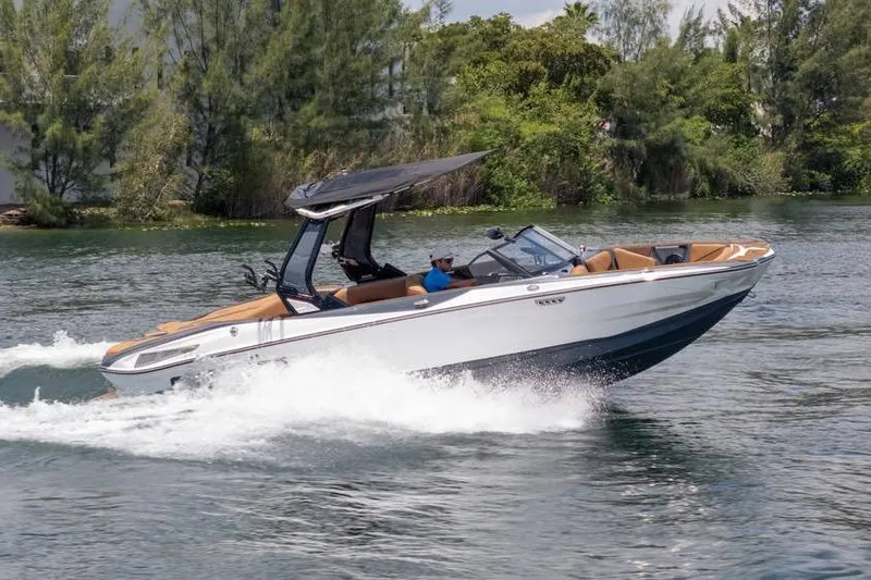 Slide: The Image of 2025 Centurion Nv233 boat cruising on a scenic lake with lush greenery. - 8