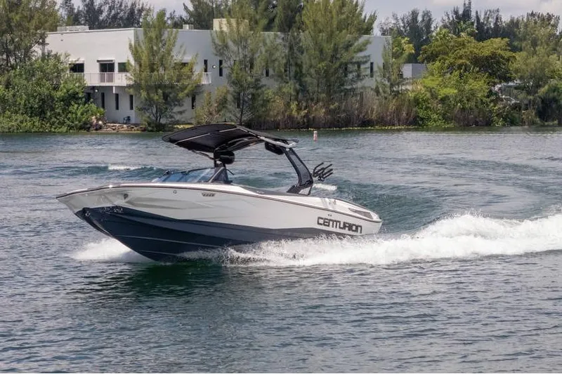 Slide: The Image of 2025 Centurion Nv233 boat cruising on a scenic lake with lush greenery. - 9