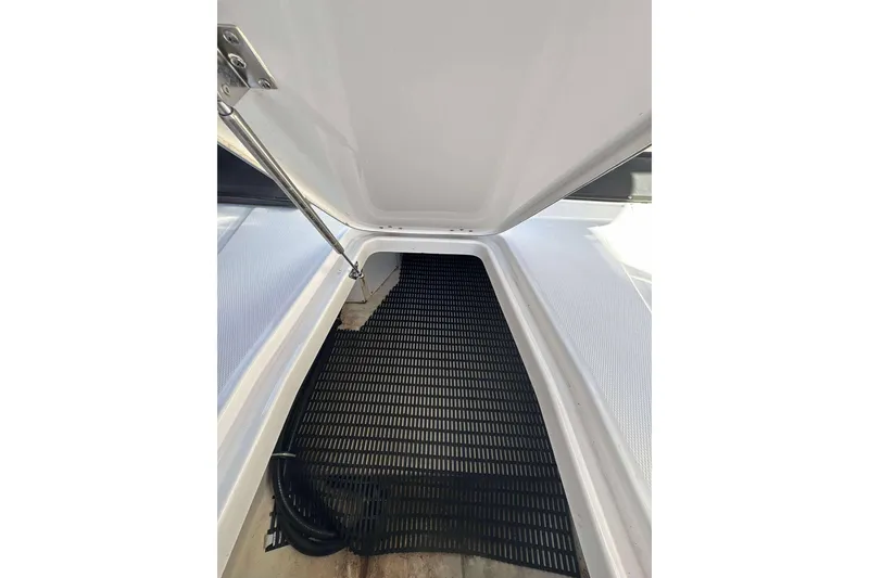 Slide: The Image of Open storage compartment in 2018 Monterey 278SS Super Sport boat, featuring black mat flooring. - 16