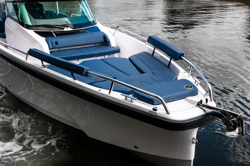 Slide: The Image of 2026 Axopar 29 Sun Top boat with blue seating on calm water. - 9