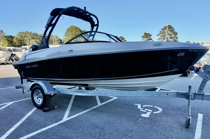 Slide: The Image of 2025 Bayliner VR4 Bowrider OB on trailer, parked in a lot with trees in background. - 4