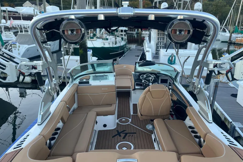Slide: The Image of 2021 MasterCraft XT21 boat interior with tan seating and modern dashboard at a marina. - 13