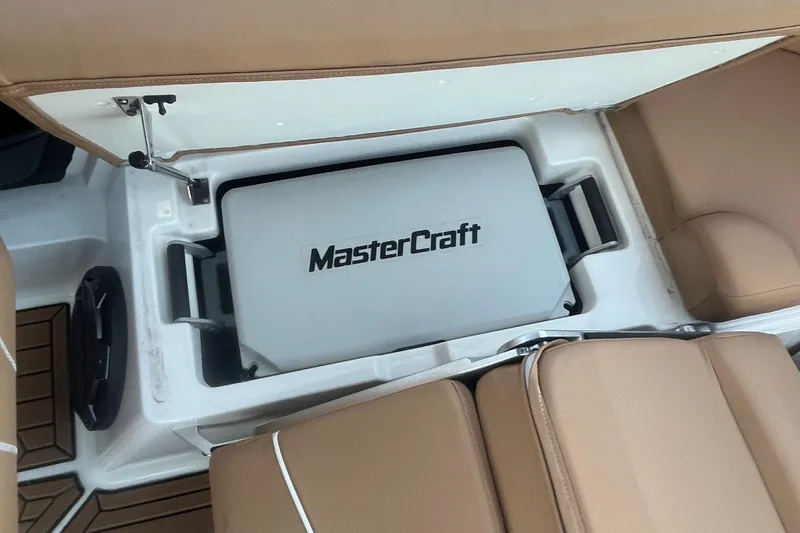 Slide: The Image of 2021 MasterCraft XT21 boat interior with storage compartment and tan seating. - 20