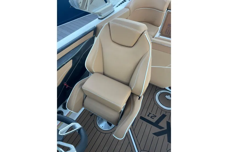Slide: The Image of 2021 MasterCraft XT21 boat captain's seat with tan upholstery and white stitching. - 22