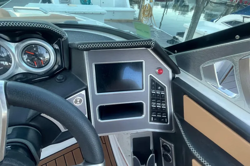 Slide: The Image of 2021 MasterCraft XT21 dashboard with modern controls and sleek design at a marina. - 24