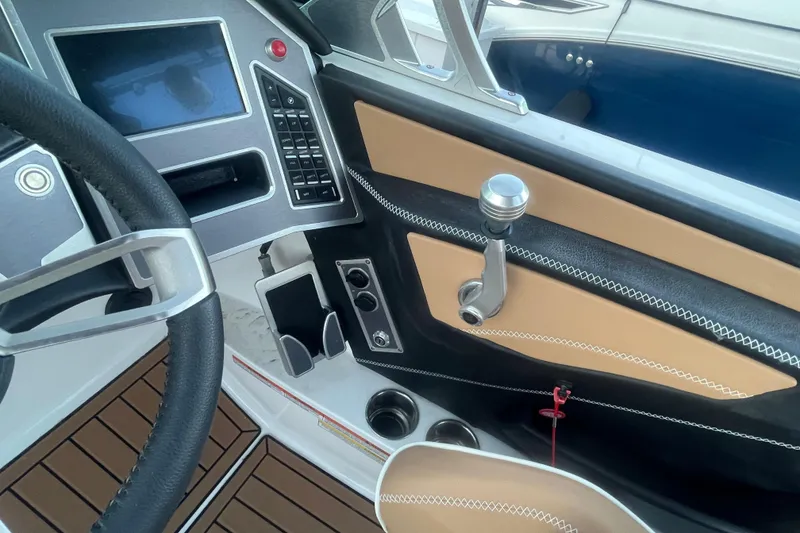 Slide: The Image of 2021 MasterCraft XT21 boat interior with steering wheel, control panel, and luxurious stitching. - 25