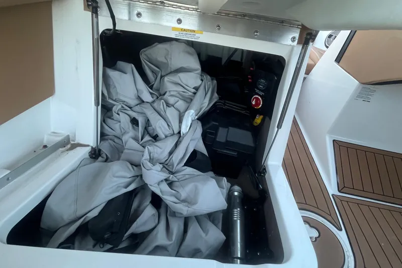 Slide: The Image of Storage compartment of a 2021 MasterCraft XT21 boat with cover and battery. - 26