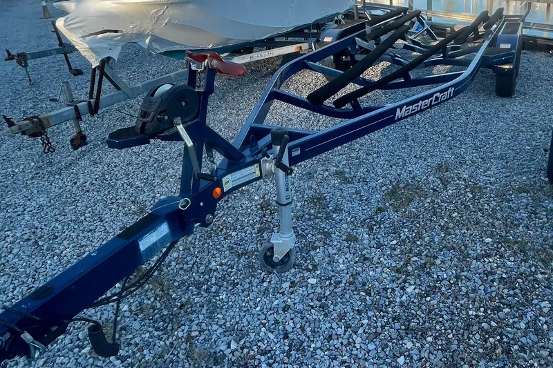 Slide: The Image of 2021 MasterCraft XT21 boat trailer on gravel surface, featuring sturdy construction. - 35