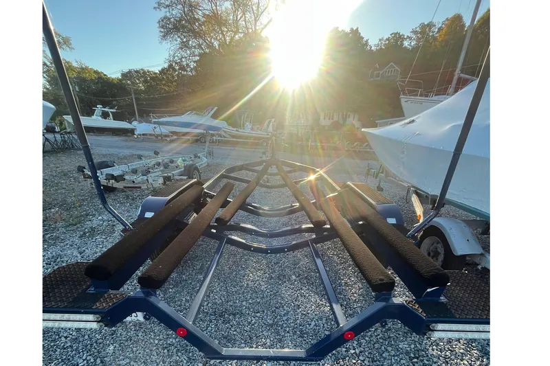 Slide: The Image of Boat trailer in sunlight, surrounded by various boats, gravel lot. MasterCraft XT21, 2021 model. - 36