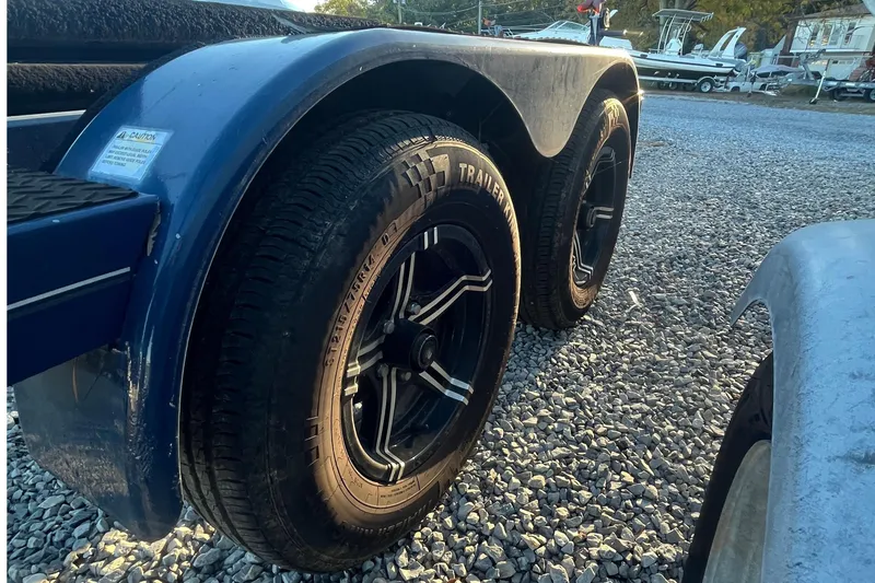 Slide: The Image of 2021 MasterCraft XT21 trailer with dual black wheels on gravel surface. - 37