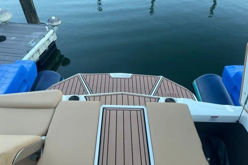 Slide: The Image of 2021 MasterCraft XT21 boat deck with tan seating and wood finish near dock. - 8
