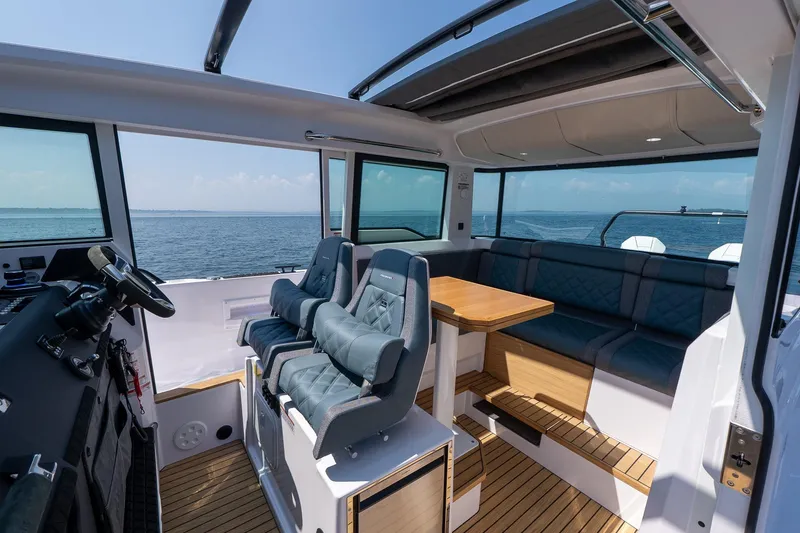 Slide: The Image of 2026 Axopar 37 Aft Cabin interior with seating, table, and ocean view. - 28