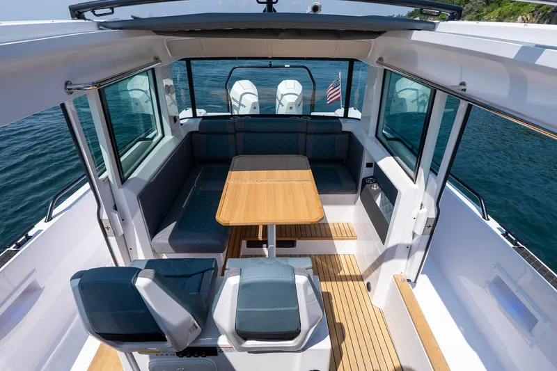 Slide: The Image of 2026 Axopar 37 Aft Cabin interior with seating, table, and scenic water view. - 34