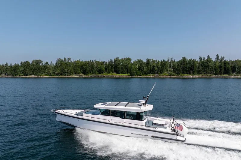 Slide: The Image of 2026 Axopar 37 Aft Cabin cruising on a serene lake with forested shoreline. - 53