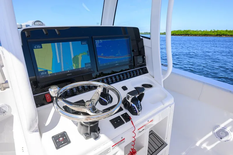 Slide: The Image of 2024 Sea Hunt Ultra 305 SE boat dashboard with navigation screens and steering wheel. - 10