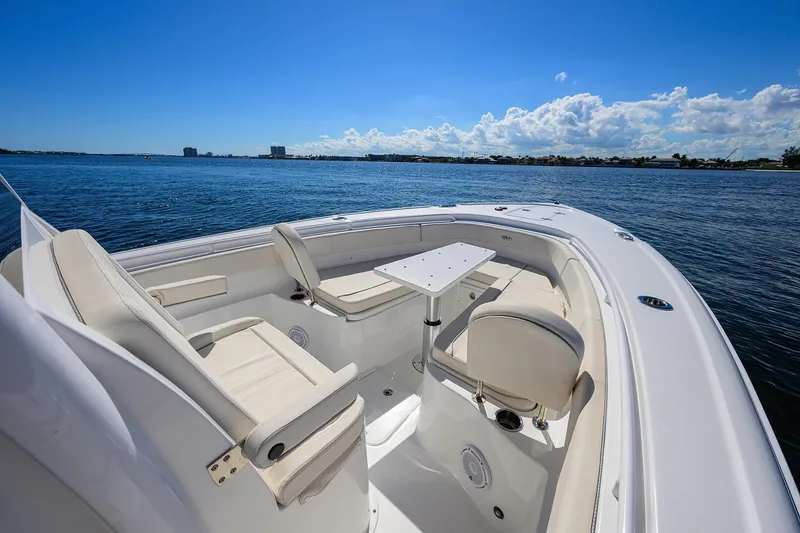 Slide: The Image of 2024 Sea Hunt Ultra 305 SE boat interior with seating and table on calm water. - 13