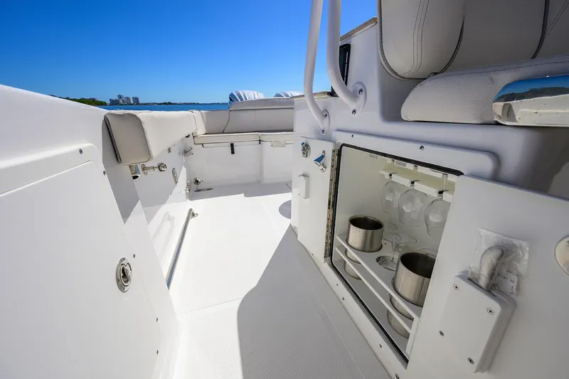 Slide: The Image of 2024 Sea Hunt Ultra 305 SE boat interior with storage and seating, under clear blue sky. - 20