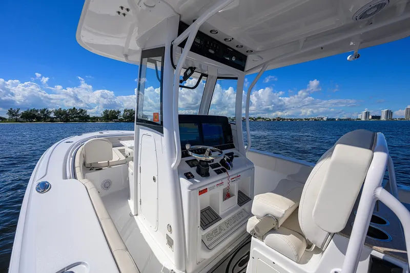 Slide: The Image of 2024 Sea Hunt Ultra 305 SE boat interior with helm, on calm water under blue sky. - 9