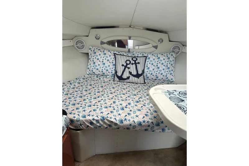 Slide: The Image of 2002 Wellcraft 2600 Martinique cabin interior with nautical-themed bedding and anchor pillow. - 12