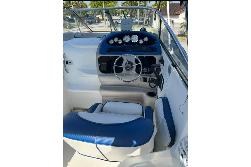 Slide: The Image of 2002 Wellcraft 2600 Martinique boat cockpit with blue and white seating, steering wheel, and dashboard. - 2