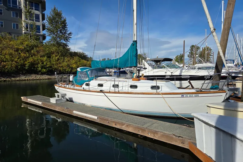 The Image of 1982 Cape Dory 33 sailboat docked at marina, clear sky, surrounded by other boats. - 1