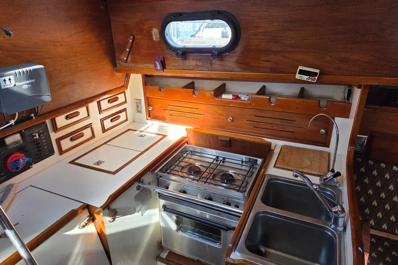 Slide: The Image of Interior of 1982 Cape Dory 33 sailboat galley with stove, sink, and wooden cabinetry. - 12
