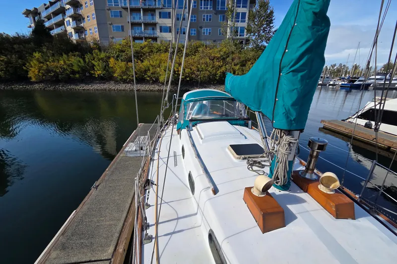 Slide: The Image of 1982 Cape Dory 33 sailboat docked near waterfront buildings and lush greenery. - 4