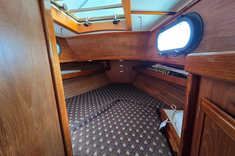 Slide: The Image of 1982 Cape Dory 33 cabin interior with wood paneling and patterned bedding. - 8