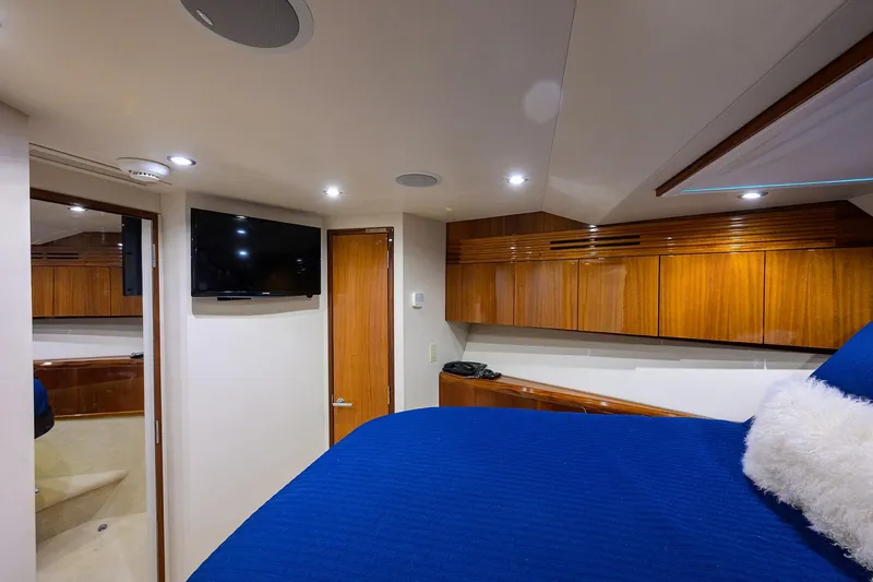 Slide: The Image of Luxurious 2009 Hatteras Enclosed Bridge yacht interior with wood cabinetry and blue bedding. - 27