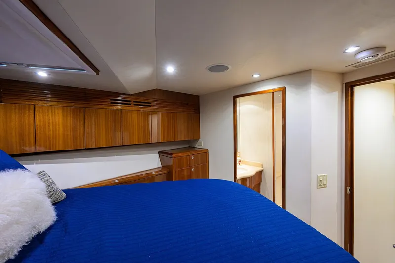Slide: The Image of Luxurious 2009 Hatteras Enclosed Bridge yacht bedroom with blue bedding and wooden cabinetry. - 28