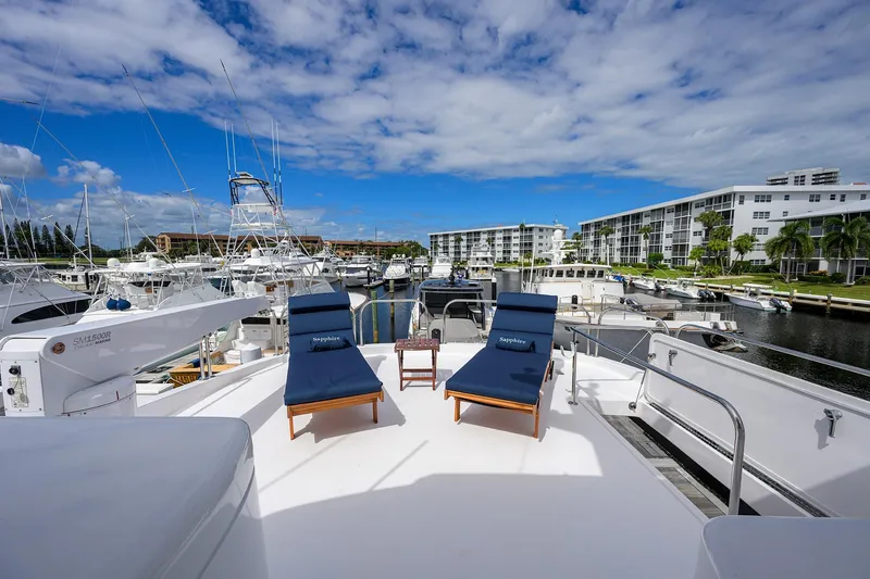 Slide: The Image of 2009 Hatteras Enclosed Bridge yacht with sun loungers, docked in a marina under blue skies. - 37