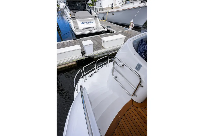 Slide: The Image of 2009 Hatteras Enclosed Bridge yacht docked, featuring sleek design and wooden deck details. - 48