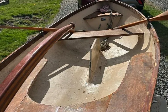 Slide: The Image of 1974 Jarvis Newman rowing/sailing dinghy with wooden oars, displayed outdoors. - 3