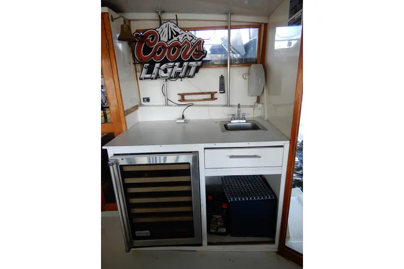 Slide: The Image of 1989 Jefferson 46 Sundeck boat interior with sink, mini fridge, and Coors Light sign. - 11