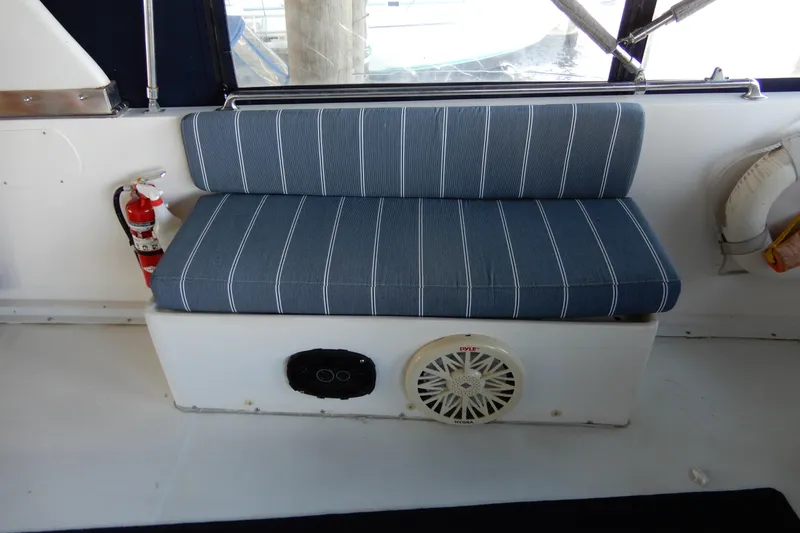 Slide: The Image of Blue-striped bench seat on 1989 Jefferson 46 Sundeck boat, featuring a speaker and fire extinguisher. - 16