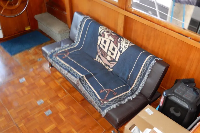 Slide: The Image of Interior of 1989 Jefferson 46 Sundeck with sofa, nautical blanket, and wooden flooring. - 28